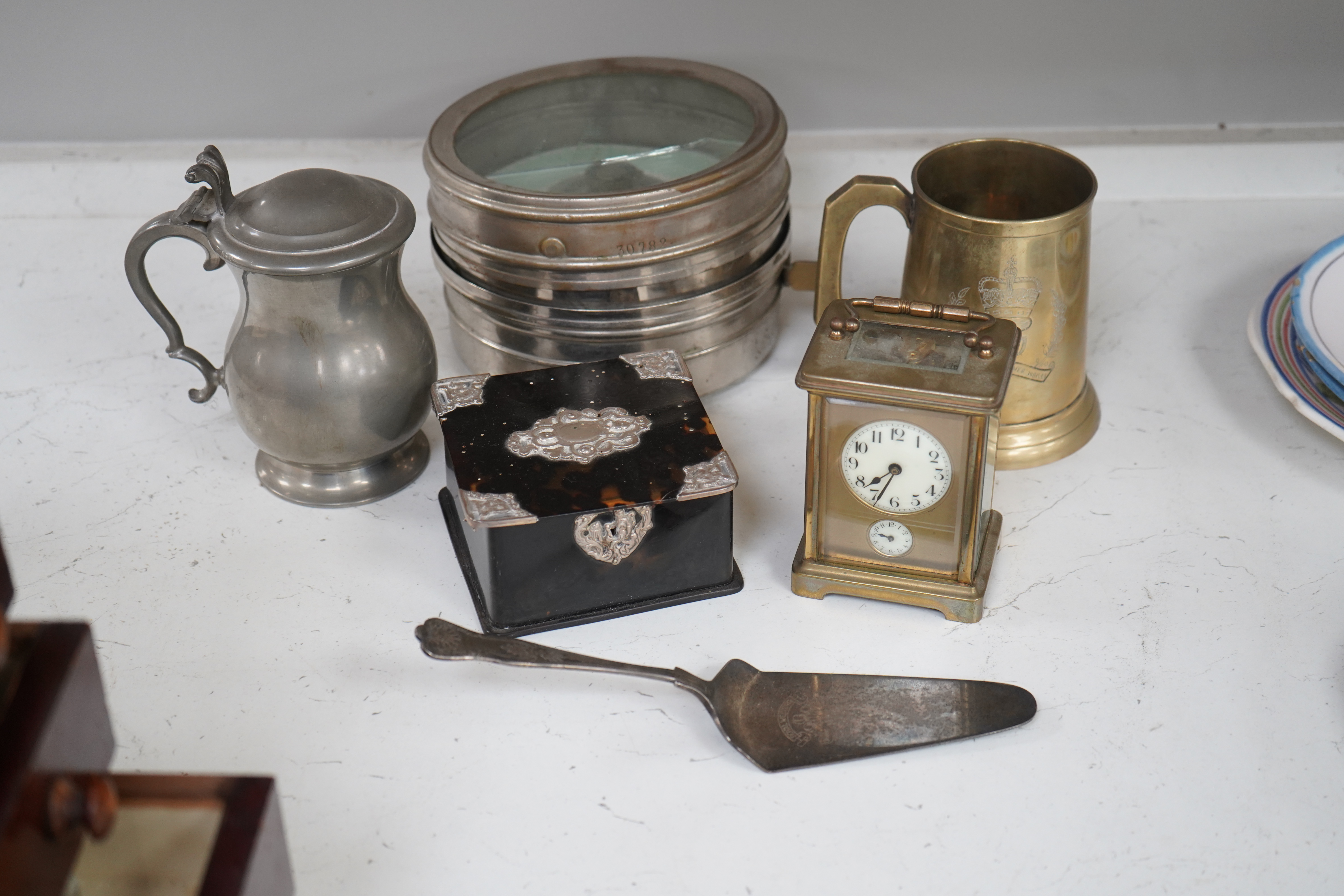 A small collection of metalware to include a white metal mounted tortoiseshell box, brass cased carriage clock with subsidiary dial and a pewter tankard. Condition - poor to fair